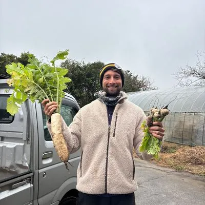 Photo of a man holding up two freshly dug up vegetables 